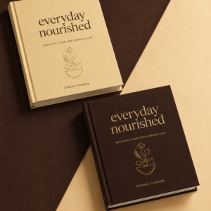Everyday Nourished cookbook shown in cream and dark brown hardcover editions